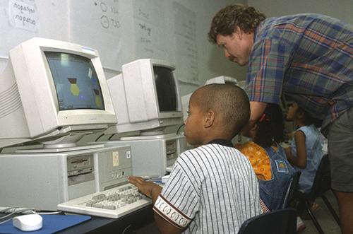 学生们在老师的帮助下摆弄旧电脑