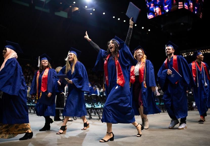 密歇根州立大学丹佛分校的毕业生们拿着毕业证书走下毕业典礼的舞台.