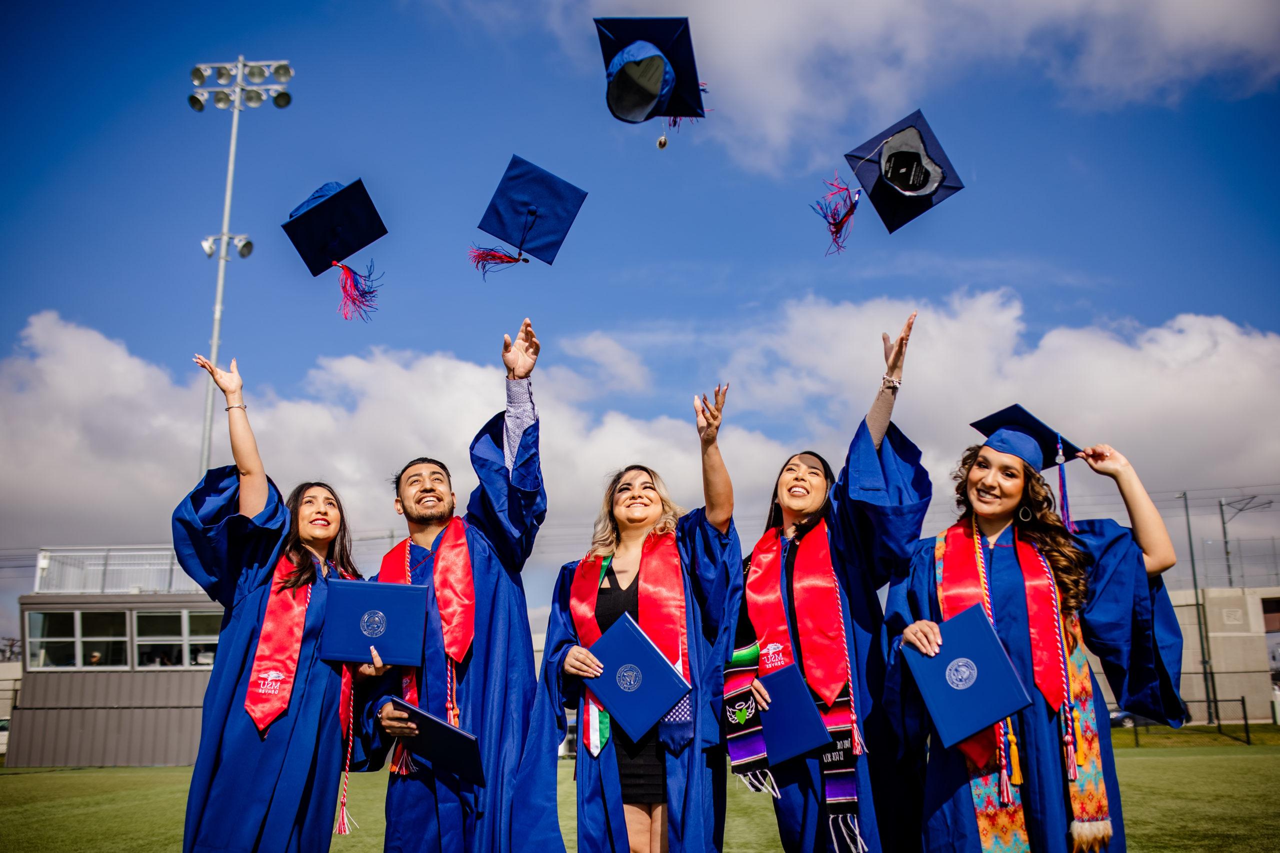 密歇根州立大学丹佛分校的学生将毕业帽抛向空中庆祝毕业